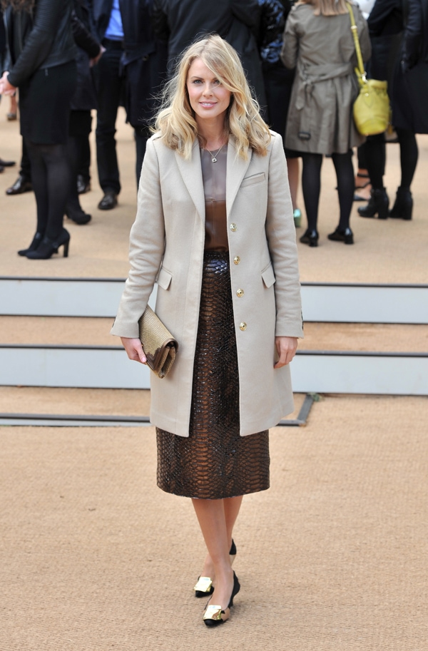 Donna Air keeps it sophisticated in a tailored taupe coat layered over a sheer blouse and textured midi skirt, finishing the look with bow-topped pumps and a woven clutch for timeless polish