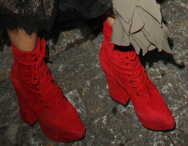 A side angle reveals the boots’ chunky block heels and ankle-grazing height, balancing their vivid color with a grounded, utilitarian edge
