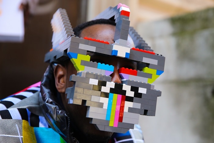 A London Fashion Week attendee turned LEGO bricks into wearable street-style art, pairing the oversized geometric face mask with a boldly patterned jacket for a surreal take on playful fashion experimentation