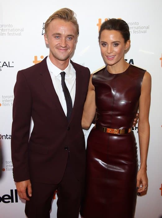 Tom Felton and Jade Olivia showcase coordinated couple style in matching oxblood Burberry ensembles at the 2013 Toronto International Film Festival, blending sleek tailoring with bold leather texture for a polished red carpet moment