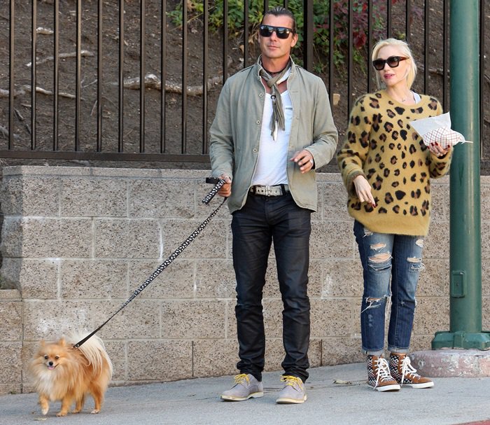 Gwen Stefani rocks an oversized leopard-print sweater with distressed denim and patterned high-top sneakers while her husband, Gavin Rossdale, complements her casual style in a light jacket, dark jeans, and a stylish two-tone scarf