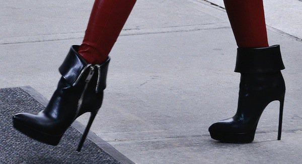 Hayden Panettiere styles her sleek black Saint Laurent ankle boots, featuring folded-down cuffs and bold side zippers, with striking red pants for a chic, height-boosting fall look
