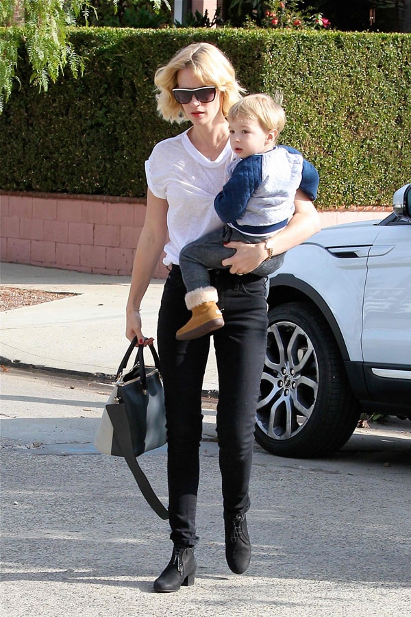 January Jones rocks a casual chic look in black skinny jeans, a white tee, and ankle boots while carrying her son