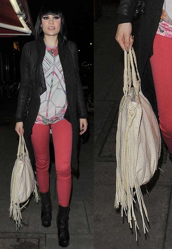 Jessie J steps out in a bold street-style look featuring coral skinny jeans, a geometric-print top, a long black coat, platform ankle boots, and a statement white fringe bag