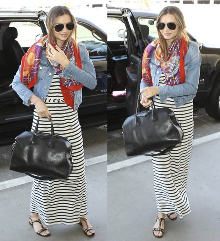 Miranda Kerr perfects effortless airport style, layering a bold printed scarf over a classic striped maxi dress and denim jacket, finishing the look with aviator sunglasses and a sleek black handbag