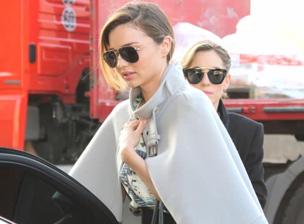 A closeup of Miranda Kerr showing her elegant street style, featuring a Chloé wool-blend cape and Oliver Peoples aviator sunglasses