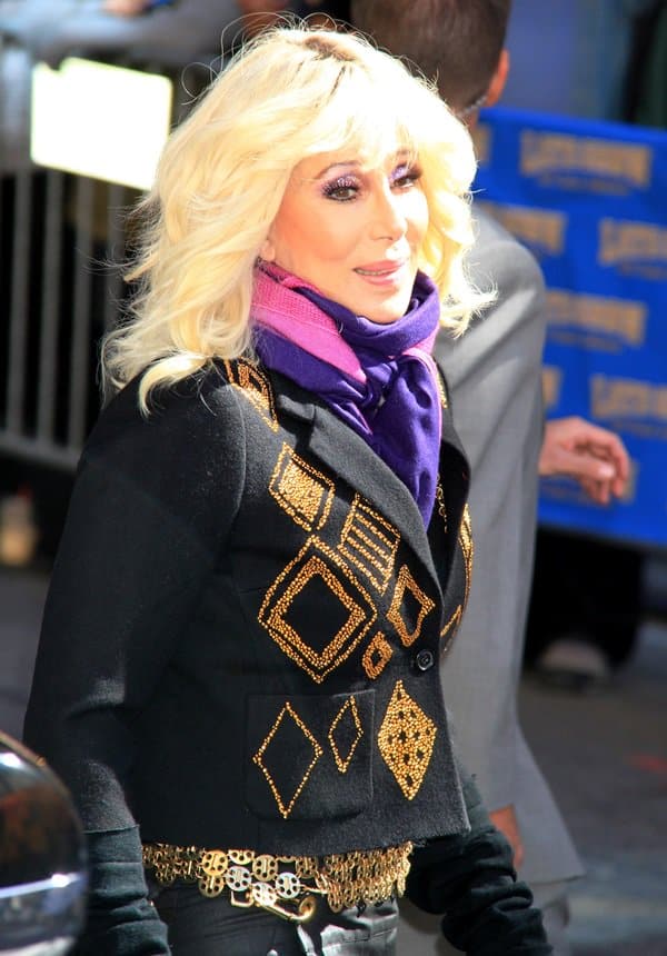 Cher shines in a striking outfit featuring a black leather jacket adorned with intricate gold designs