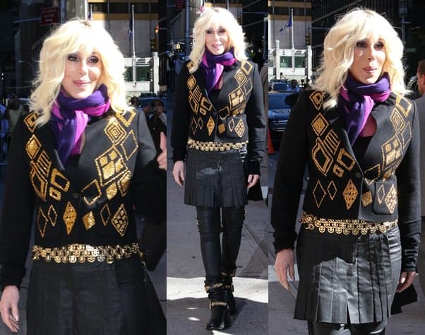 Cher dazzles in a unique ensemble featuring a black leather jacket adorned with intricate gold designs, paired with a matching skirt and leggings