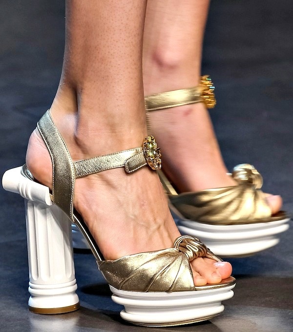 Gold Dolce Gabbana high-heeled sandals featuring unique Doric column heels and jeweled embellishments epitomize the brand's blend of classic and opulent design