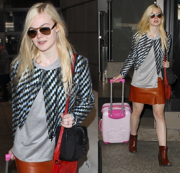 Elle Fanning arrives at LAX from Paris in a chic Kenzo jacket, Phillip Lim leather skirt, and Maison Martin Margiela ankle boots, pulling a pink Hello Kitty suitcase
