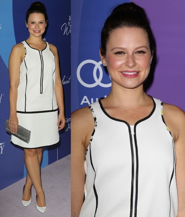 Katie Lowes keeps it sleek and modern in a structured white Sportmax dress with black trim, pairing it with classic L.K. Bennett pumps, a metallic clutch, and a chic high bun for a polished, monochrome look