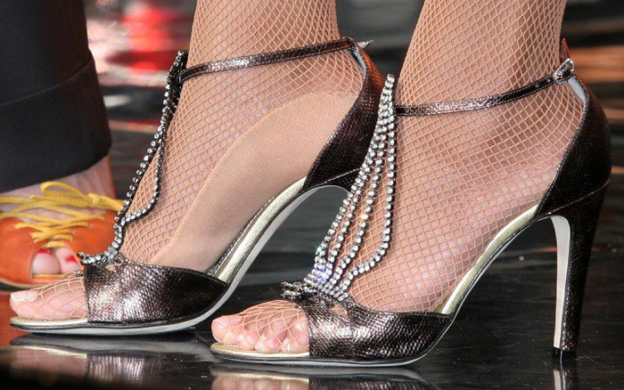 Beyoncé adds a glamorous touch to her performance with shimmering T-strap heels adorned with crystals, paired perfectly with fishnet stockings for a bold, stylish look