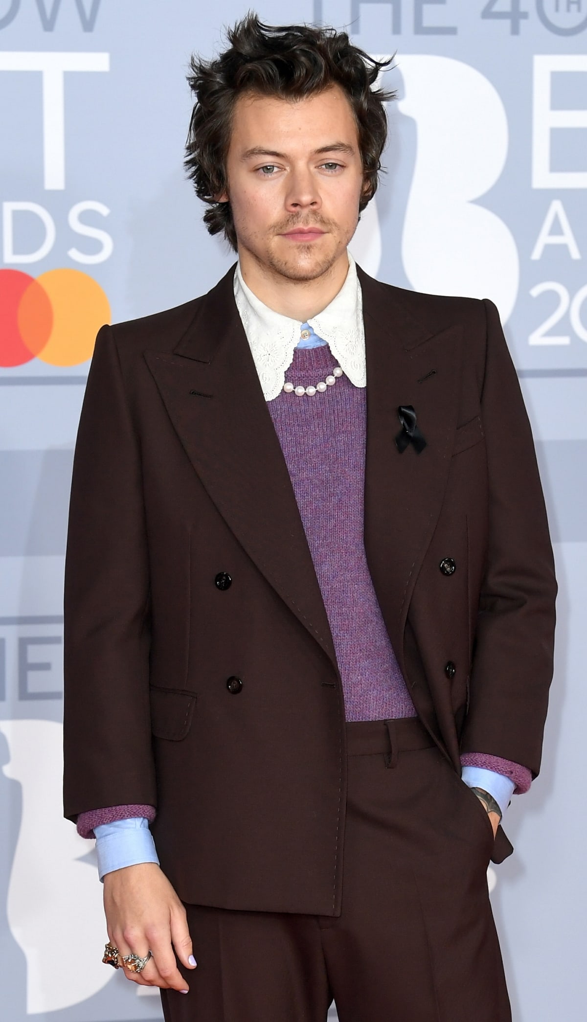 Harry Styles paid tribute to the late Caroline Flack, former Love Island host, by wearing a black ribbon on his Gucci suit's lapel at the 2020 BRIT Awards