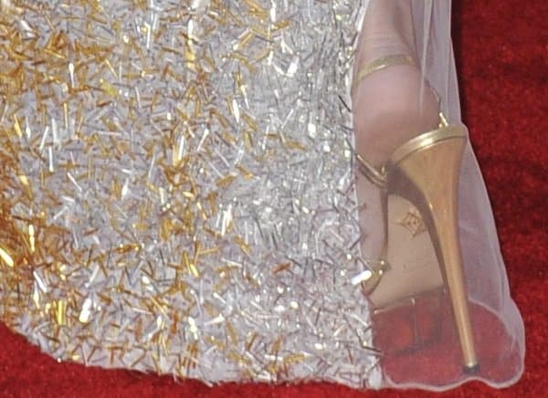 She completed the shimmering look with gold Charlotte Olympia “Gilda” platform sandals peeking through the hem of her dress