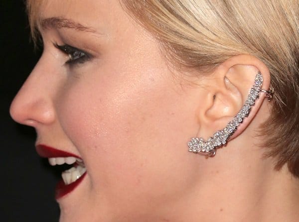 A close-up shot highlights Jennifer Lawrence's elegant wingtip earrings, designed by Anita Ko, completing her red-carpet ensemble