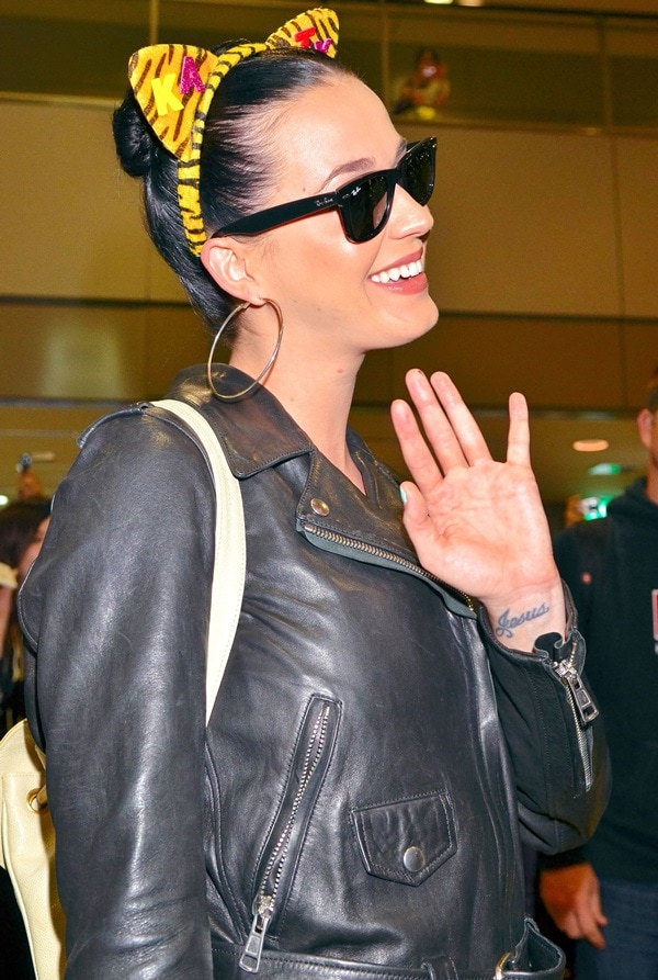 Katy Perry sports Ray-Ban Original Wayfarer 2140 sunglasses, a black signature Acne moto jacket, and a fun leopard-print headband upon her arrival at Narita International Airport in Japan on October 30, 2013