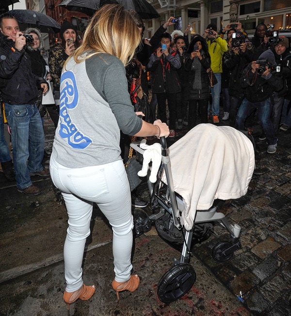 Kim Kardashian keeps it casual in a baseball tee and white skinny jeans, pushing baby North’s stroller while elevating the look with strappy Gianvito Rossi heels