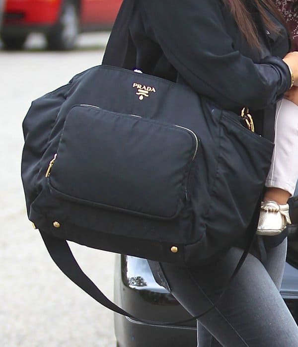 Kourtney Kardashian carries a luxurious black Prada Vela nylon diaper bag, featuring gold-tone hardware and multiple compartments for a chic yet functional motherhood accessory