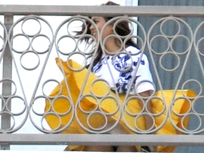 Kourtney Kardashian struggles with a gusty breeze while on the balcony of the Eden Roc Hotel in Miami, battling the wind with her vibrant yellow skirt