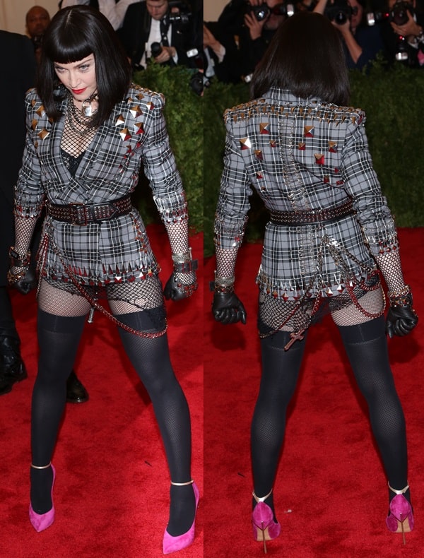 Madonna embraces punk-inspired rebellion at the 2013 Met Gala in a studded tartan Givenchy jacket layered over fishnet tights, leather gloves, chained accessories, and towering pink-and-black Casadei heels, turning the “Punk: Chaos to Couture” dress code into a deliberately provocative head-to-toe fashion statement