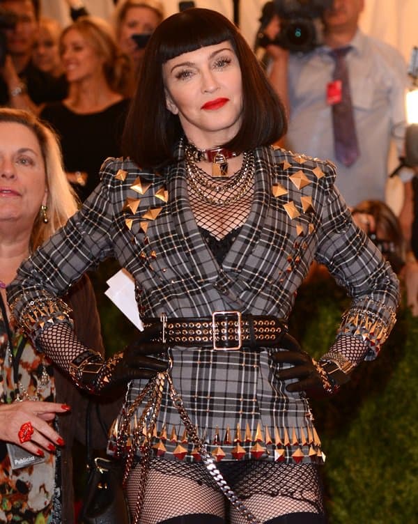 Madonna poses inside the 2013 Met Gala in a tailored plaid Givenchy look trimmed with metallic pyramid studs, cinched with a wide grommet belt