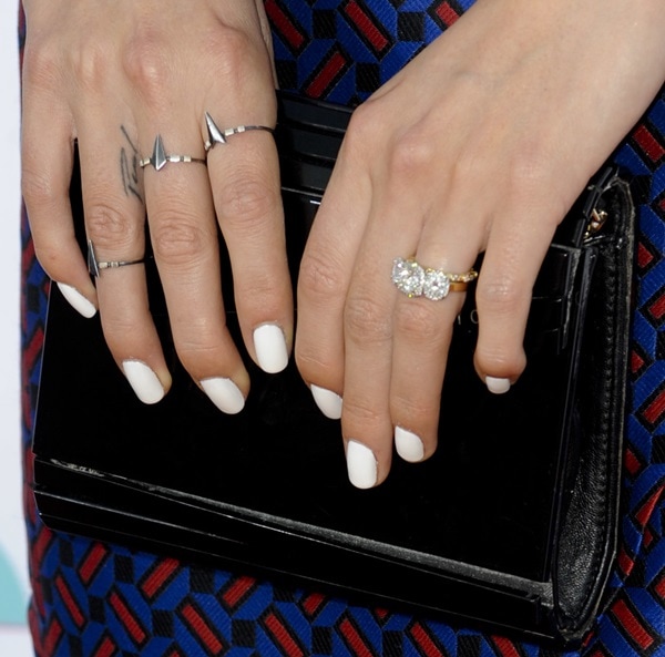 Nikki Reed shows off white nails, stacked rings, and her subtle “Paul” finger tattoo while holding a black clutch at the TeenNick HALO Awards