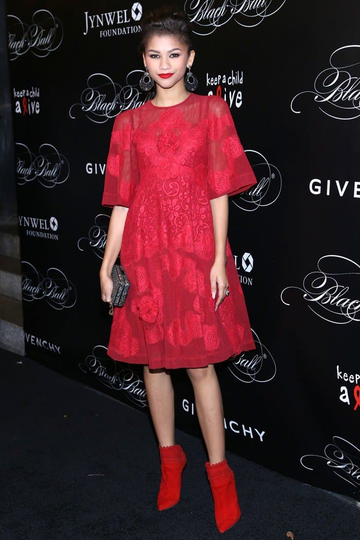 Zendaya elevates her monochromatic moment with bold red Tabitha Simmons “Harmony” ankle boots that perfectly echo the rich lace texture of her Dolce Gabbana dress