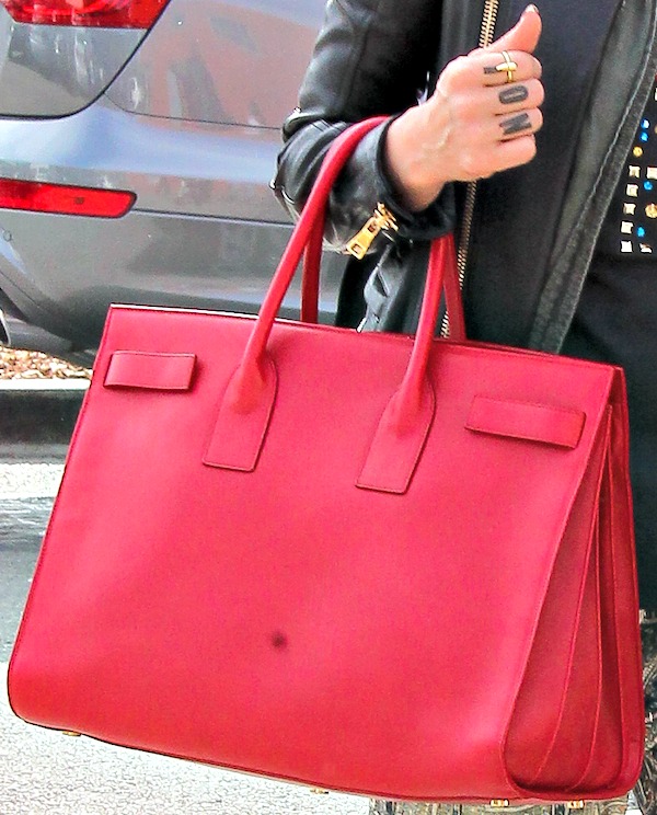 She elevates her look with a bold red Saint Laurent “Sac de Jour” tote that adds a pop of color