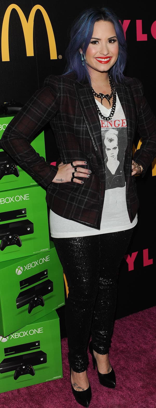 Demi Lovato rocked a chic ensemble at the Nylon Magazine Cover Party on December 5, 2013, featuring Karl sequined legging-style pants, a Marissa Webb Isabelli Addington plaid jacket, Saint Laurent black leather pumps, a Cartier pink gold diamonds love bracelet, a Luv Aj cross tusk necklace and prism earrings, Hudson Krista vice versa super skinny sequin jeans, and a Maison Martin Margiela knuckleduster ring set