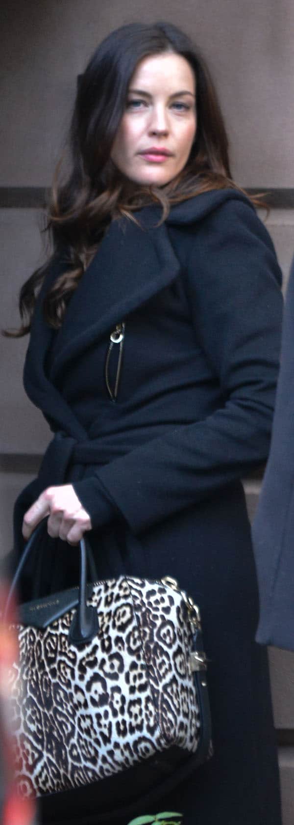 Liv Tyler looking stylish in a black coat with a leopard-print handbag
