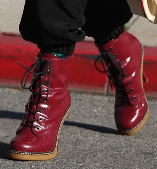 Gwen Stefani makes a bold statement in glossy red L.A.M.B. Nichol patent lace-up platform booties, adding a vibrant pop of color and edgy polish to her monochrome street-style look