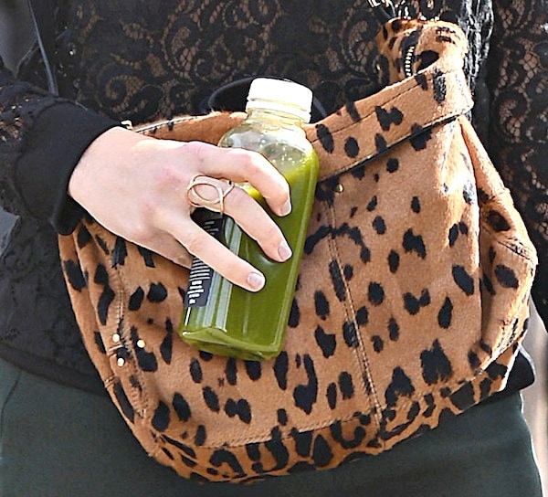 Mandy Moore accessorizes with a trendy leopard-print messenger bag, perfectly complementing her chic outfit while carrying a refreshing green juice