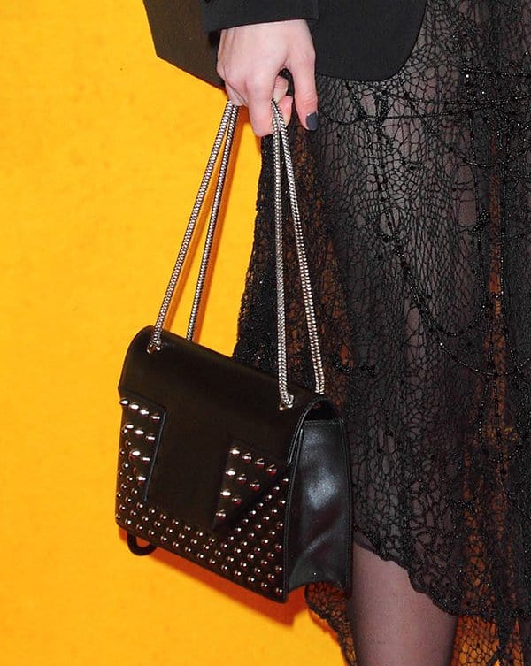 Daisy Lowe carries a black Saint Laurent "Betty" bag with silver-tone studs and a polished curb chain handle, perfectly complementing her sheer lace dress at 'The Wolf of Wall Street' UK premiere