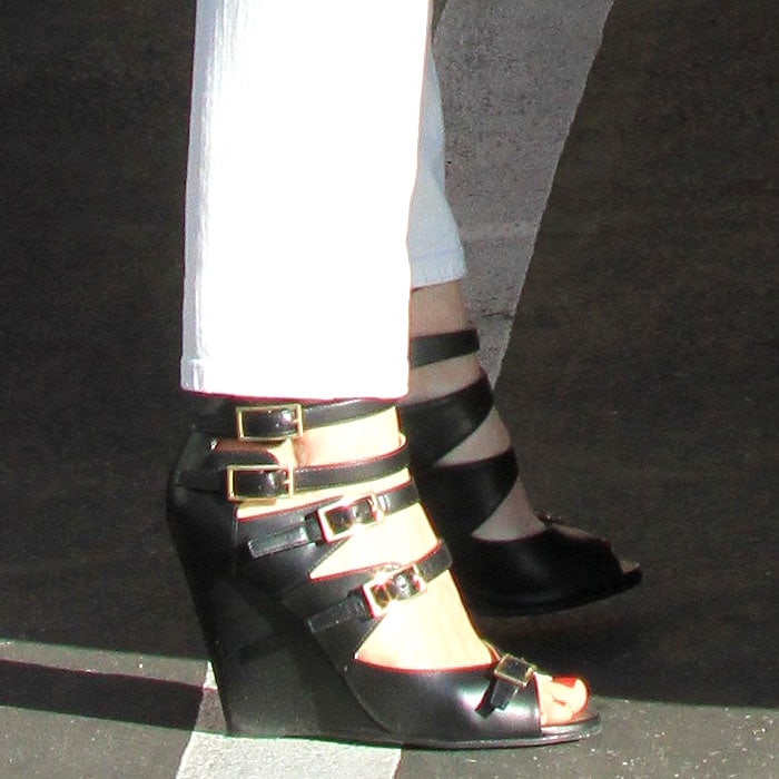 January Jones shows off a neutral pedicure in bold black Chloé “Arce” multi-buckled wedge sandals, their strappy, architectural design adding striking contrast to her white denim