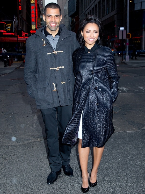 Kat Graham paired glossy black patent Casadei “Blade” pumps with a textured double-breasted coat while posing alongside fiancé Cottrell Guidry in New York City
