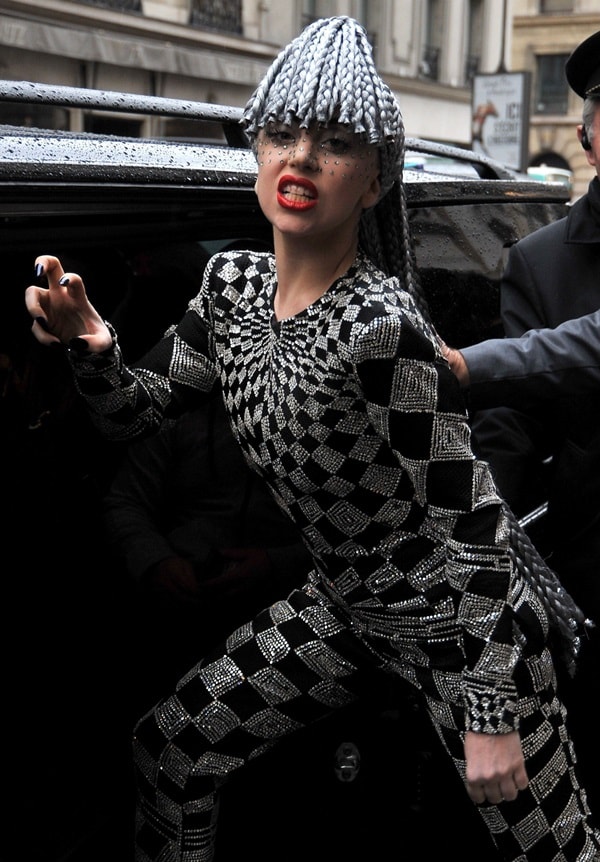 The singer channels her theatrical energy in the same vintage Versace look, striking a fierce pose that highlights the outfit’s harlequin pattern
