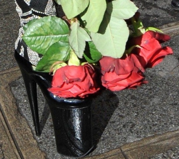 A close-up reveals Gaga’s ultra-high black patent platform heels peeking out beneath the embellished Versace jumpsuit