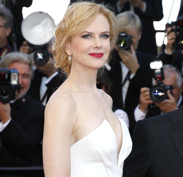 Nicole Kidman radiates timeless beauty in a plunging white gown, with her classic red lip and soft curls complementing her graceful presence at the Cannes Film Festival