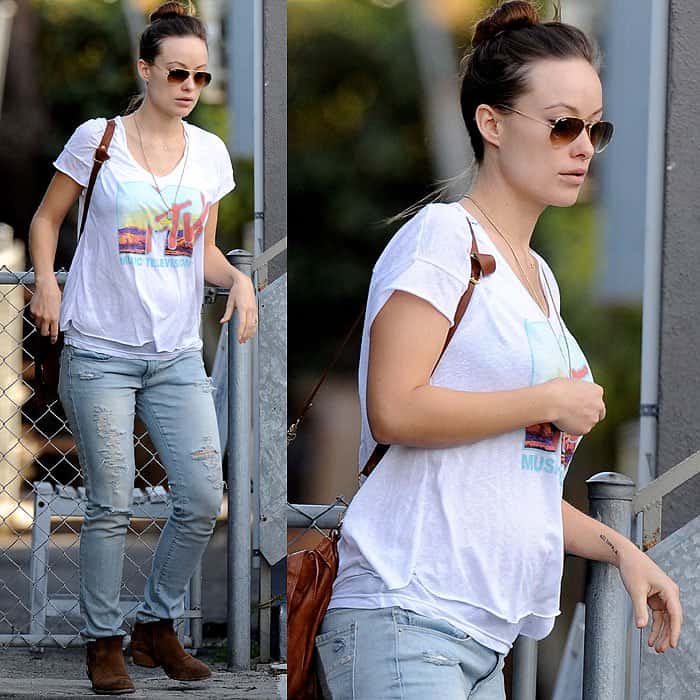 Olivia Wilde channels laid-back grunge maternity style in distressed skinny jeans, a loose MTV graphic tee, aviator sunglasses, and brown ankle boots