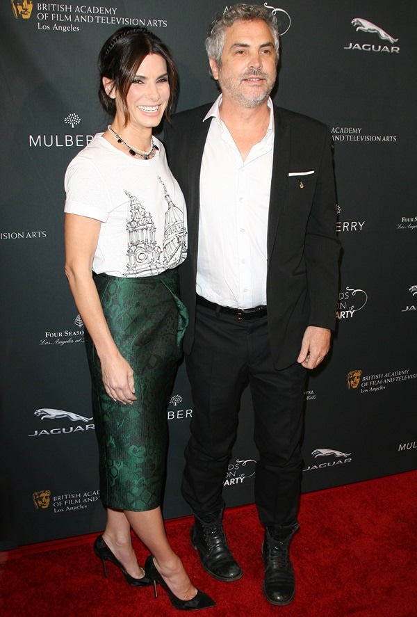 Sandra Bullock and Alfonso Cuarón pose on the red carpet as her black Casadei suede-and-mesh pumps sharpen the edgy silhouette of her Burberry Prorsum ensemble