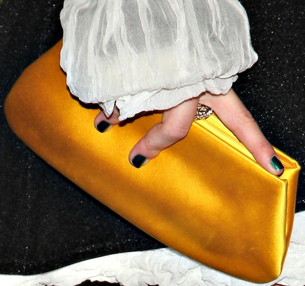 Julianne Hough adds a pop of color to her monochrome Chanel ensemble with a sleek amber-gold satin clutch that injects a modern, youthful touch into her Parisian-inspired look
