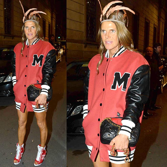 Anna Dello Russo departs the Moschino Fall 2014 show in Milan, embodying Jeremy Scott's playful aesthetic in a red and black varsity-inspired mini-dress, red high-top sneakers, a quilted black bag, and a whimsical feathered headpiece