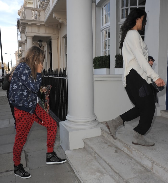 Cara Delevingne steps out in studded wedge sneakers and bold red heart-print pants, while Michelle Rodriguez keeps it comfy in grey suede boots and a slouchy sweater as they return home together in London on March 6, 2014