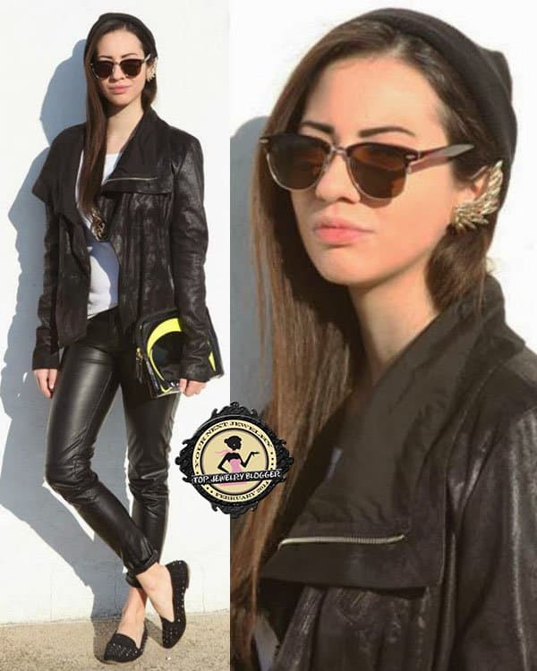 Christy rocks a black jacket over a white top, sleek black pants, black studded shoes, and a beanie