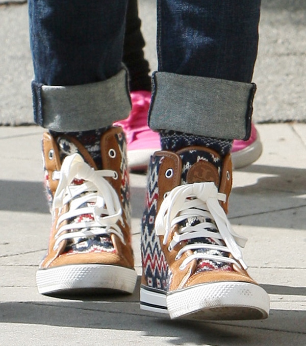 Jessica Alba’s feet in Tory Burch “Noah” hi-top sneakers featuring brown suede panels and a colorful Fair Isle knit pattern, adding a cozy, statement twist to her rolled-up jeans