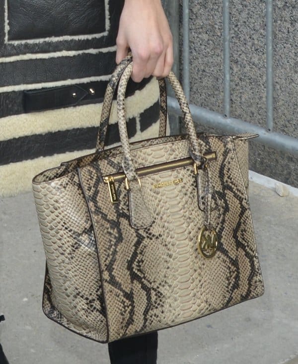 Close-up of Karlie Kloss’ python-print Michael Kors tote, featuring gold-tone hardware, a structured silhouette, and the brand’s signature medallion charm