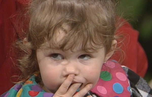 A young Miley Cyrus makes an early television appearance, charming viewers with her playful expression and colorful polka-dot outfit