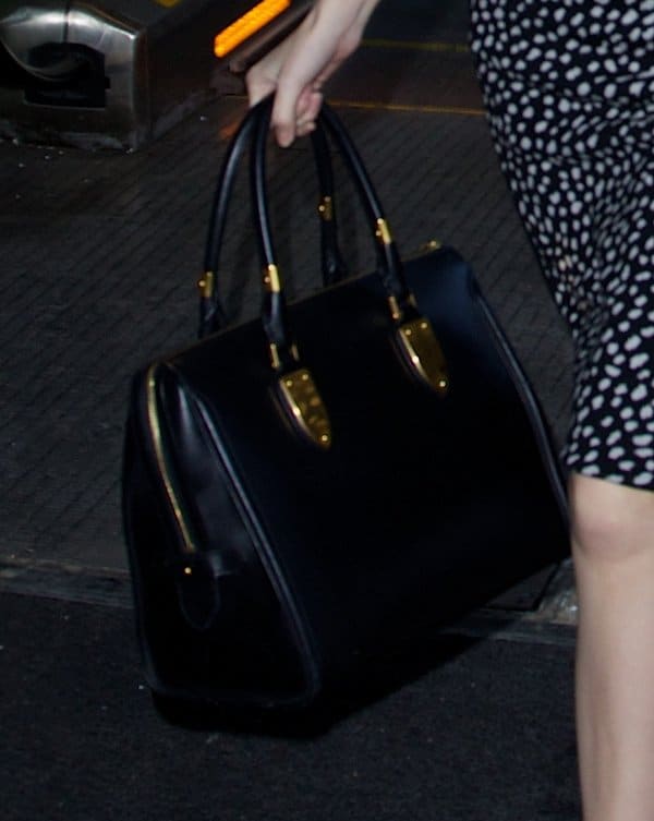 Close-up of Anna Kendrick’s black Alexander McQueen Heroine tote, featuring structured leather, gold-tone hardware, and rolled top handles