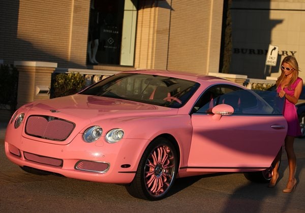 Paris Hilton makes a statement in her custom pink Bentley Continental GT, matching her vibrant magenta dress as she steps out in style