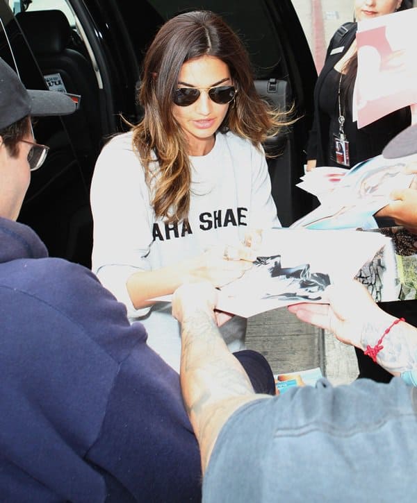 Shielded by classic Ray-Ban aviators, Lily Aldridge signs autographs in a relaxed Kings of Leon sweatshirt